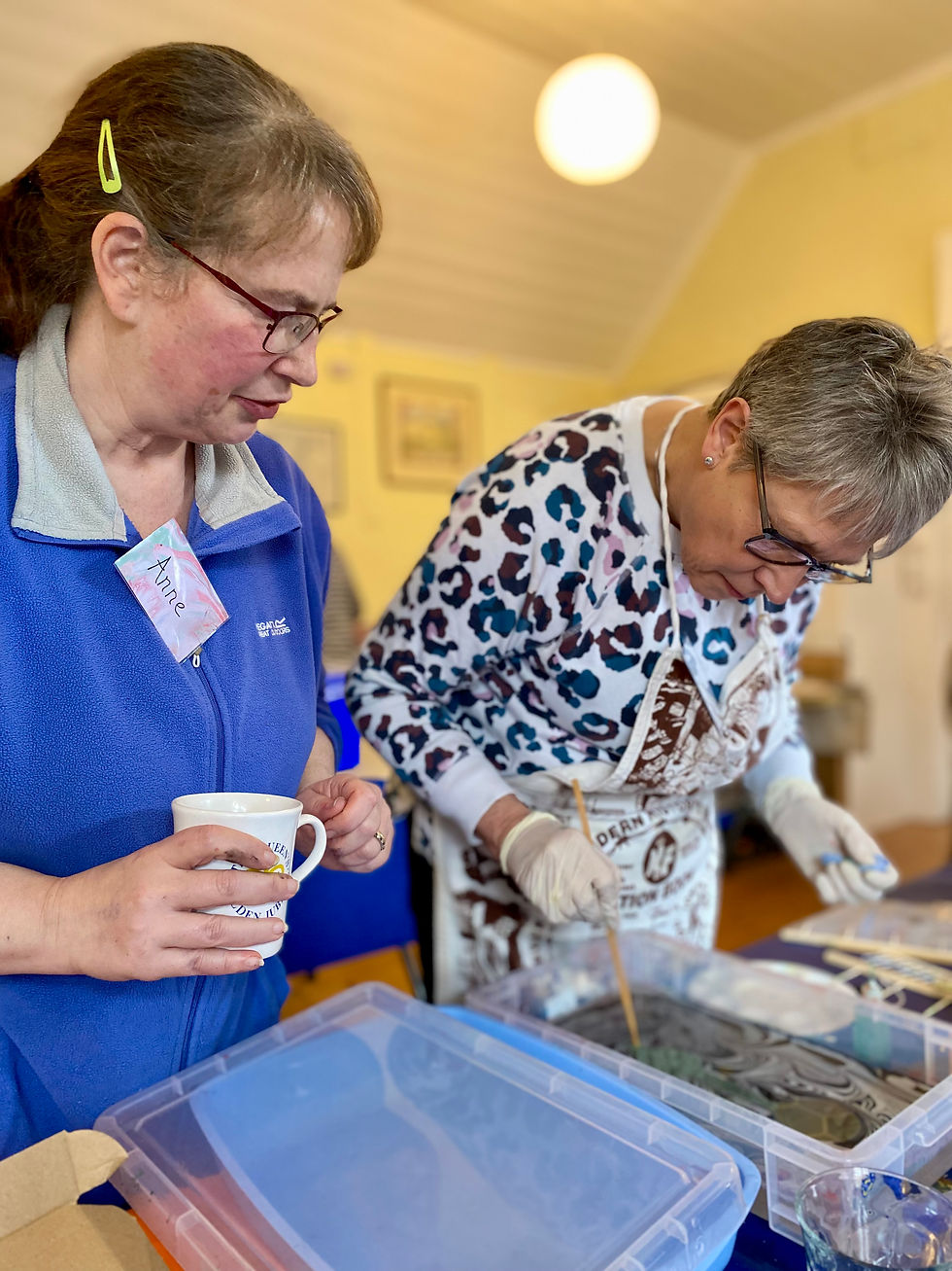 Anne Hickley watching a customer create colourful marbled paper during a marbling workshop at Reef Make & Do in North Norfolk.