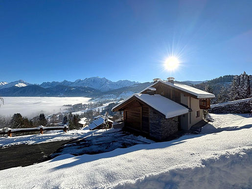Chalet en bois enneigé avec montagnes et vallée nuageuse