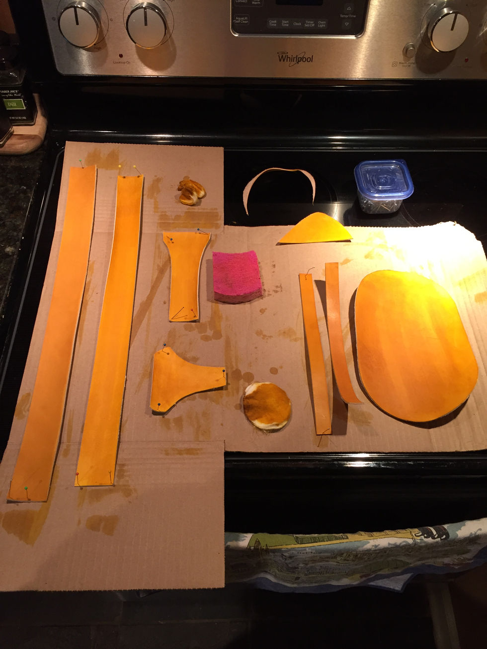 Leather pattern pieces, freshly dyed yellow lay on a big piece of cardboard.