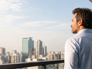 Hombre contemplando la ciudad desde un balcón.