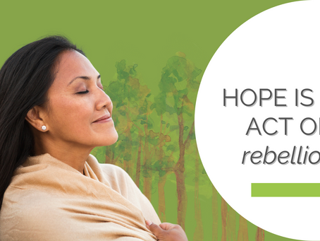 Woman with closed eyes, wrapped in a tan shawl, against a green forest background. Text: "HOPE IS AN ACT OF rebellion" on white.