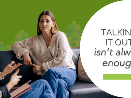 Two women sit on a sofa, engaged in conversation. One listens intently, wearing a cream sweater. Green background with text: "TALKING IT OUT isn't always enough."