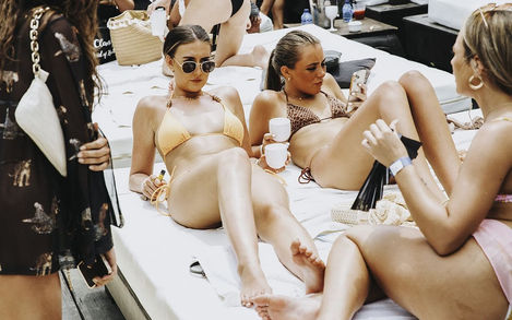 Group of women toasting drinks by the pool during hen weekend