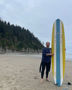 Surf coach standing with a surfboard at Short Sands beach