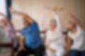 Senior people stretching while sitting on chairs at retirement home.jpg