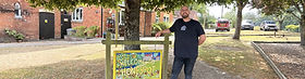 A man standing by a house sign