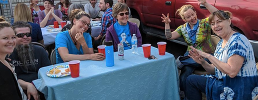 group of volunteers sitting around table for lunch and smiling