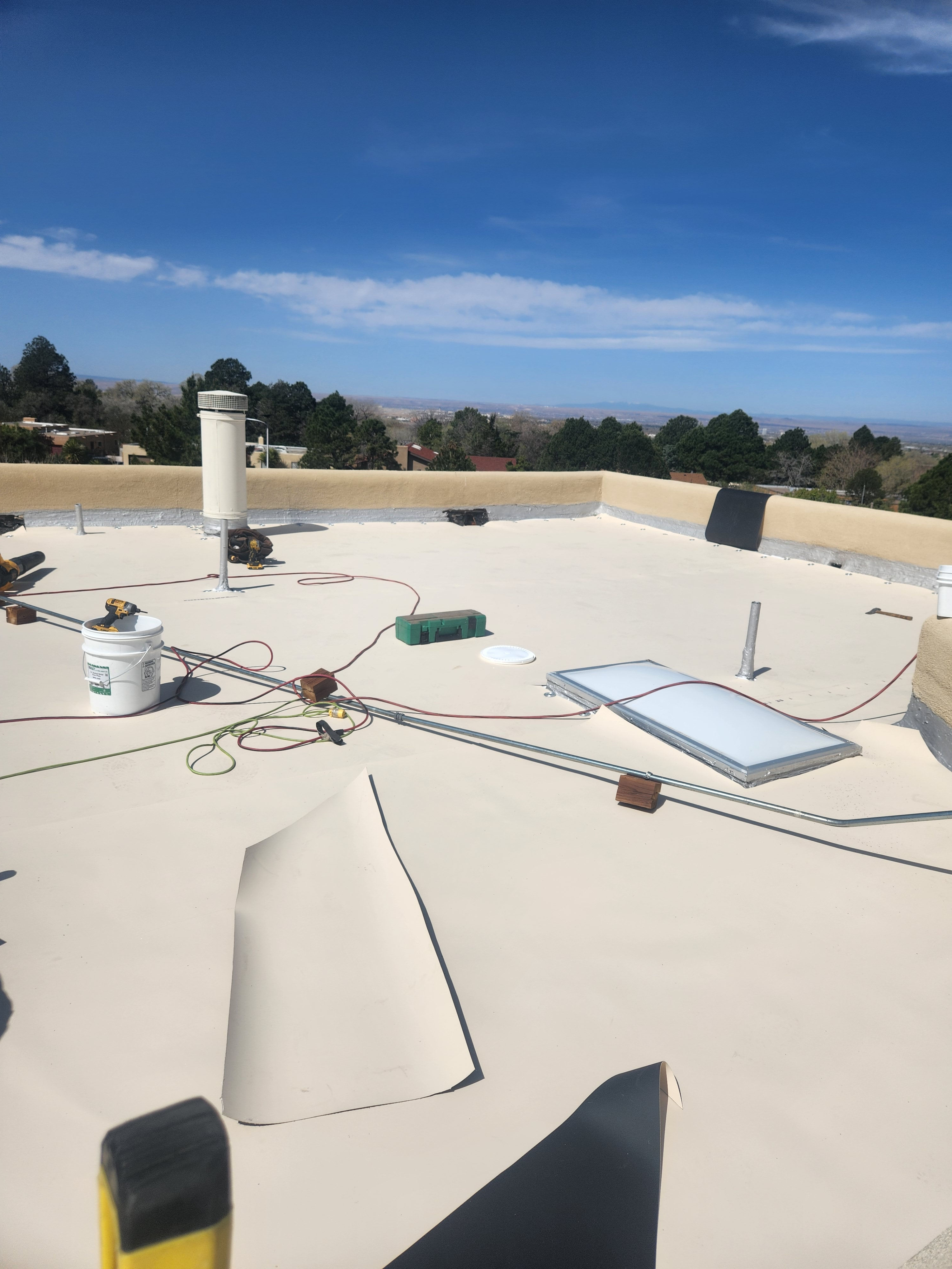 White flat roof on a sunny day. Shingle Roofing and clear blue sky.