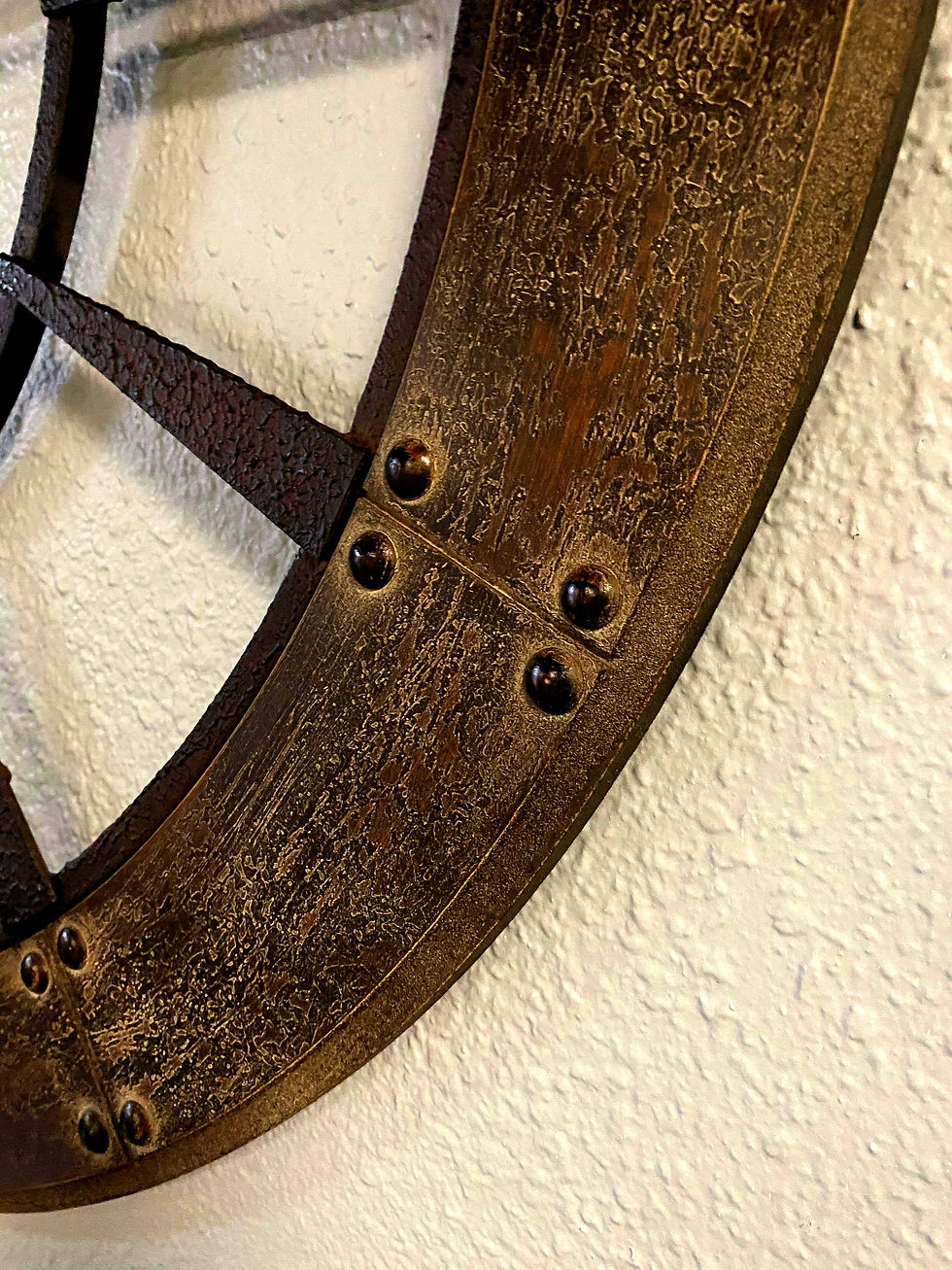 Thumbnail: Close-up of decorative metal wheel with rivets, rustic design background.