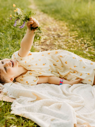 tyttö makaa viltillä ulkona kukkakimppu kädessä