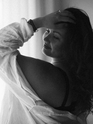 nainen koskettaa hiuksiaan tunnelmallisessa boudoir-kuvauksessa Maikki Wuoriston kanssa.