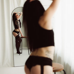 nainen katsoo itseään peilistä alusvaatteissa.