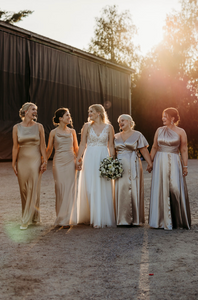 morsian ja kaasot kävelevät auringonlaskussa