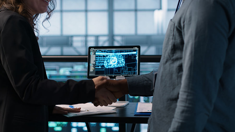 Two people shaking hands in an office. A computer screen shows a digital brain image. Papers and blue pen are on the table.