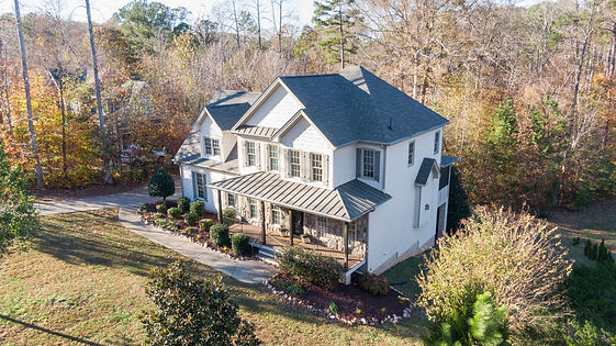 Beautiful aerial view of a charming two-story house in an autumn forest setting in Wake Forest, NC