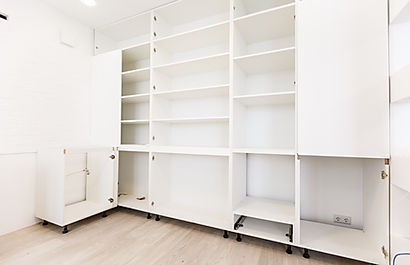 modern white closet with multiple open shelves, compartments, and built-in outlet