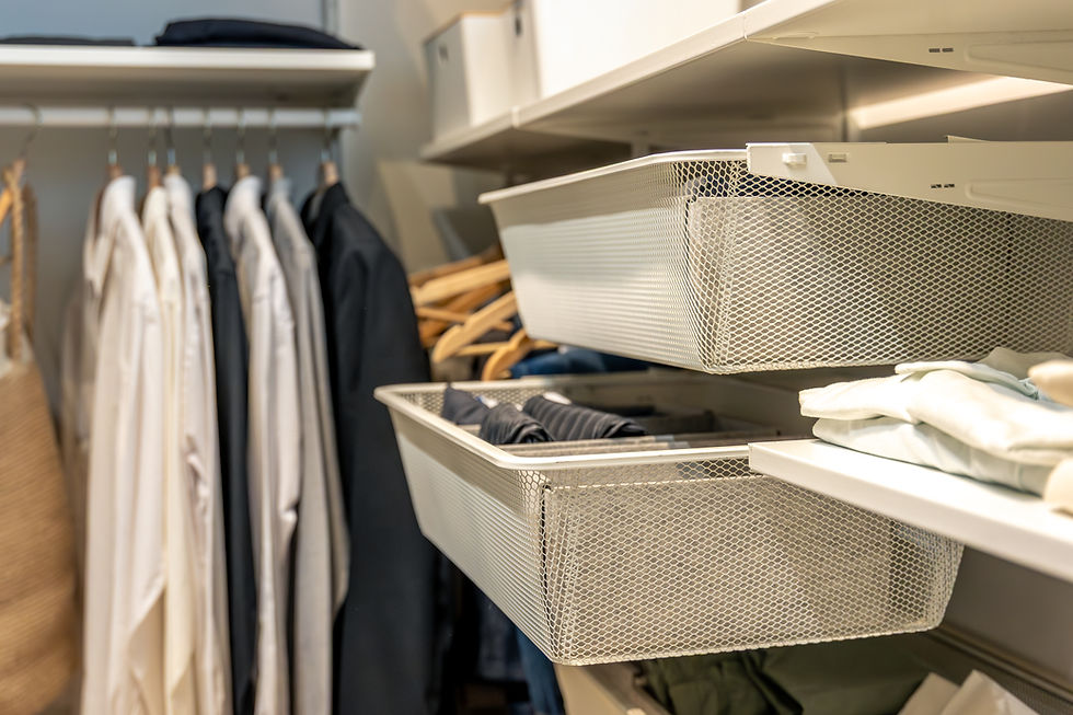 Organized walk-in closet with hanging shirts and mesh drawers holding folded clothes.