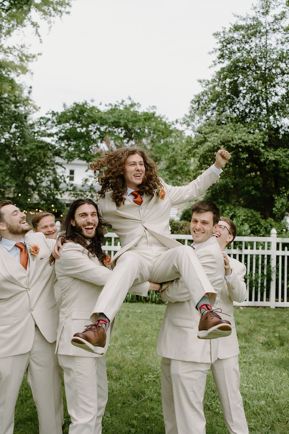 Joyful wedding celebration with groomsmen lifting a person