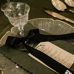 Elegant wedding table setting with menu and black ribbon.