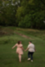 Couple holding hands by Analea Wedding Co. in a field.