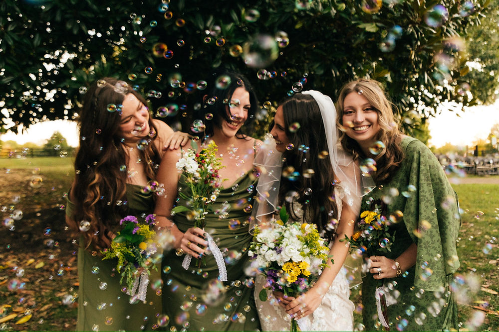 Happy bride and bridesmaids celebrating a wedding with bubbles.