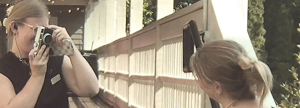 Woman taking a photo on a deck with an instant camera.