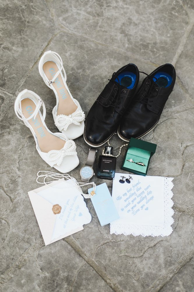 Wedding shoes, rings, watch, and stationery on stone.