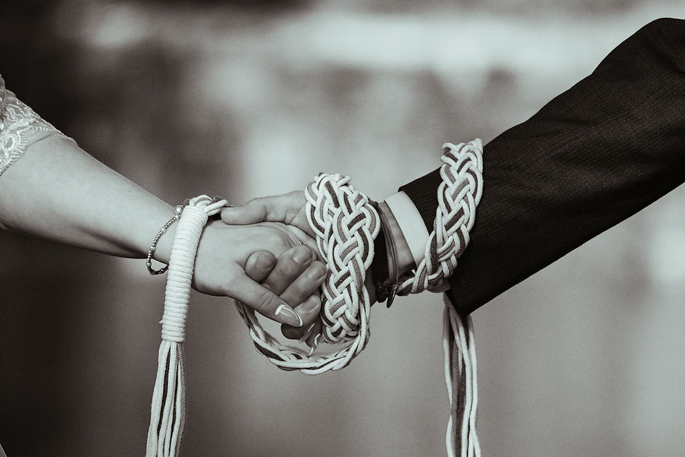Hands tied with braided cords during a wedding ceremony