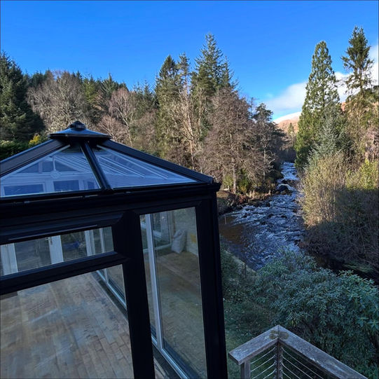 Glass conservatory view of frosty river and winter trees