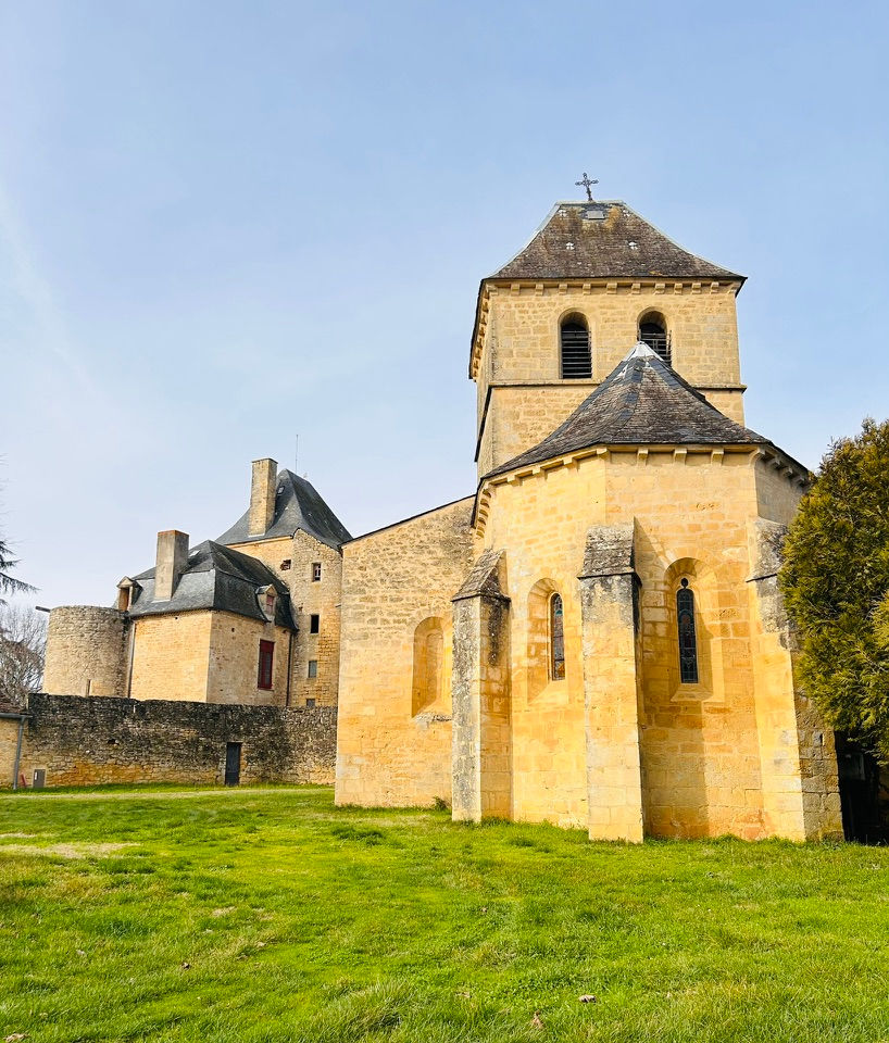 A beautiful yellow stone church in the foreground with the Chateau of Masclat in the background