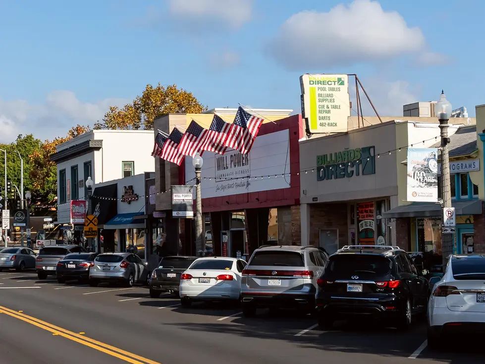 Street view with shops, cars, and American flags.