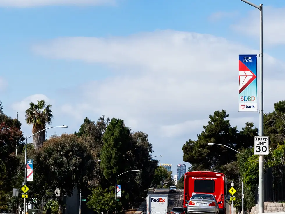 Street with vehicles and "Shop Local" banners.