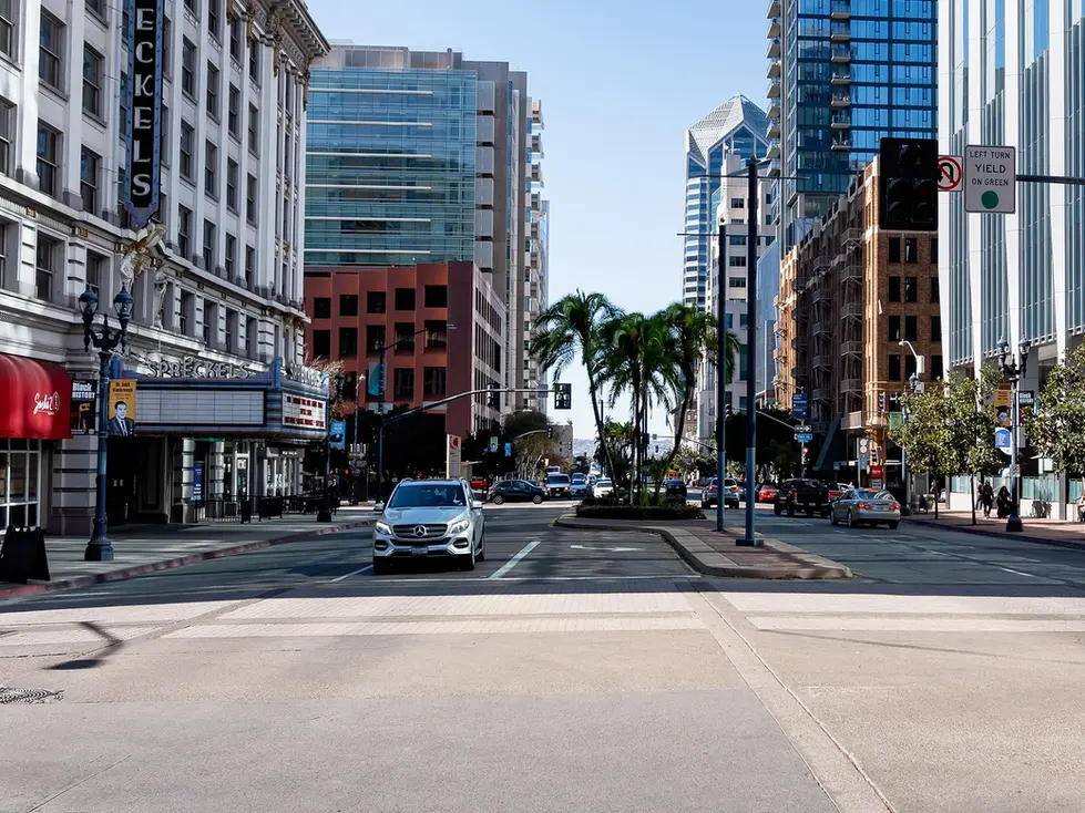 City street with cars, buildings, and palm trees.