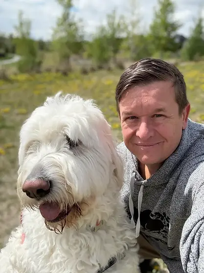 Nicholas outdoors with a large white dog in his care