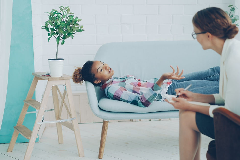 A young girl talking with a therapist on a couch during a child behavioral therapy session in Irvine