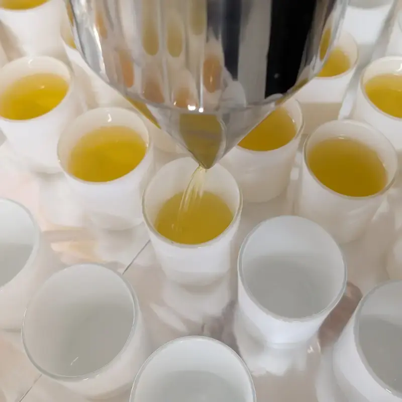 Coulage à la main de cire naturelle dans des contenants de bougies artisanales, dans l’atelier Souffle de Gaïa, pour illustrer la fabrication d’une bougie lithothérapie française.