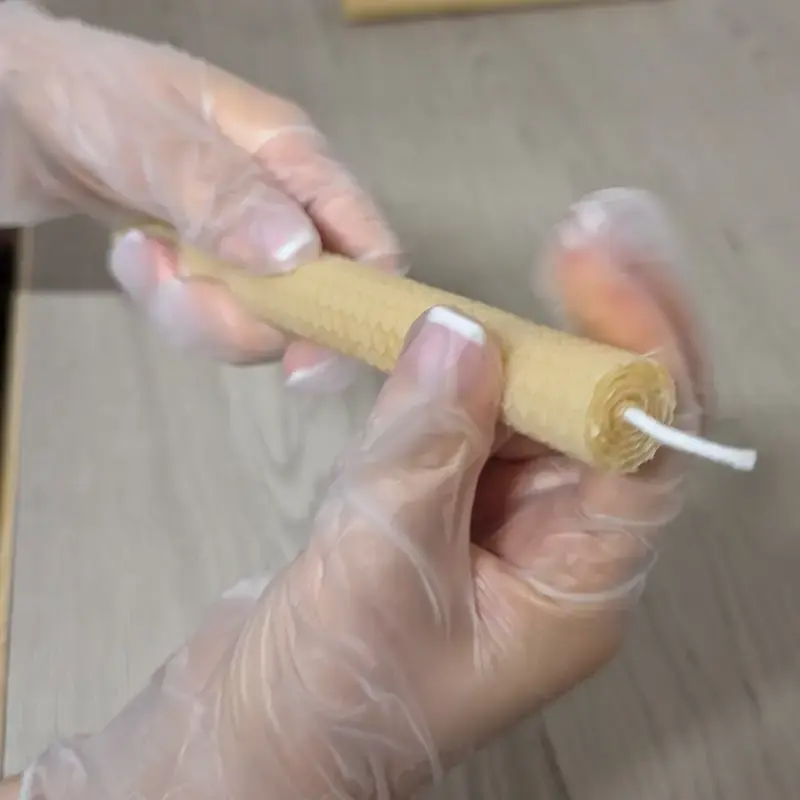 Créatrice roulant une bougie artisanale en cire d’abeille dans l’atelier Souffle de Gaïa.