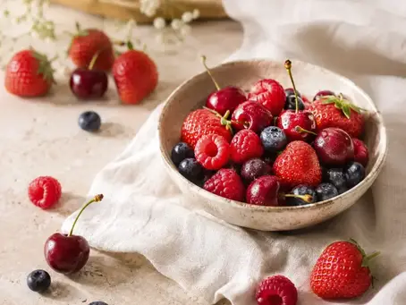 Bol en céramique rempli de fraises, framboises, cerises et myrtilles sur un linge en lin ivoire, dans une ambiance lumineuse et raffinée évoquant la senteur Fruits rouges.