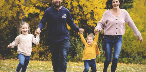 family of four running through grass in south glenmore park by Calgary photographer