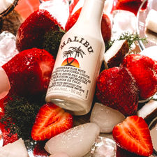 Malibu coconut rum shot lying in a bed of strawberries and ice cubes shot by calgary branding food product photographer