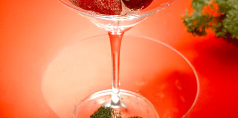 a martini cocktail glass filled with strawberries shot on a red background with white flowers by calgary product branding photographer