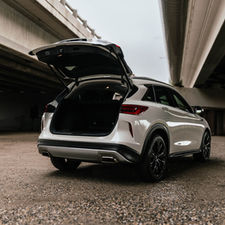 Infiniti SUV with rear hatch open underneath a bridge