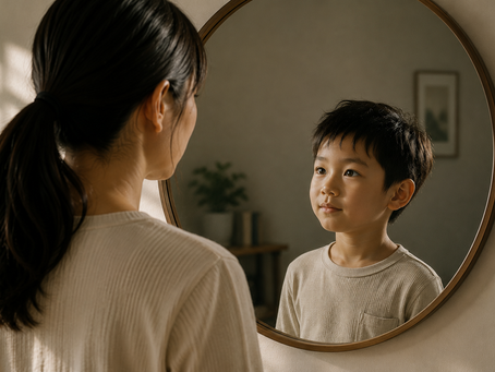 An Asian mother looks into a mirror where a young boy gazes back with confidence and curiosity, symbolising how children reflect the adults around them.