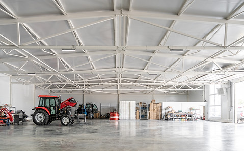 Agricultural machinery and storage area in modern industrial warehouse with tractor, shelv