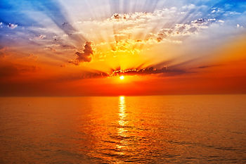 Dramatic ocean sunset with sun rays illustrating the impact of annuity income on Medicare IRMAA premiums.