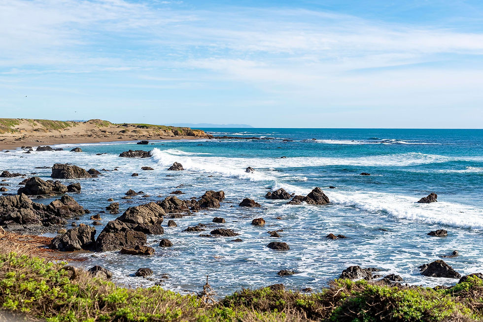 Waves breaking over a rocky shoreline under a blue sky