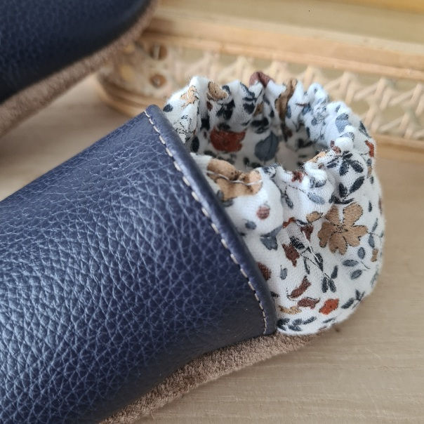 Miniature : Gros plan sur les fleurs d’automne et la texture du chausson en cuir souple bleu du modèle Fleurs d’Automne.