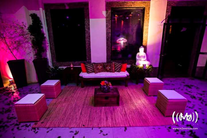 lounge criativo com estátua zen, mesa de centro com baú de madeira, flores, paisagismo, tapete e puffs de palha