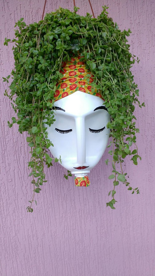 decoração de pote de plástico (de sabão liquido), com olhos e bigode pintados, e uma planta imitando cabelo.