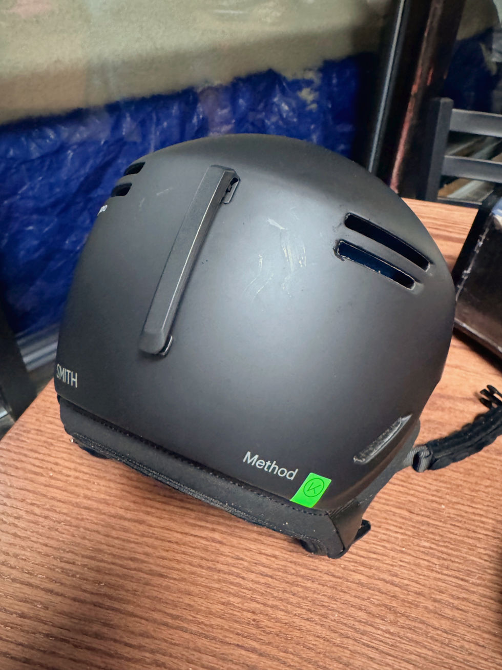 Black Smith helmet with vents and "Method" text on wood table. Background features blue and beige blurred colors.